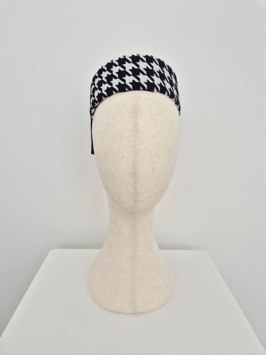 Black and white houndstooth pillbox headpiece on a mannequin head against a light gray background