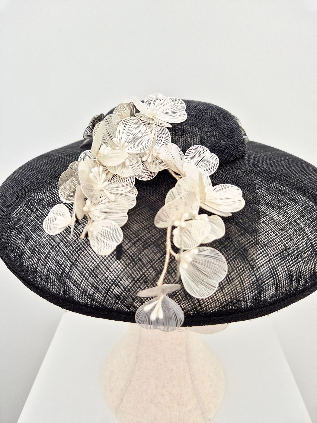 black straw hat with silver white flowers close up