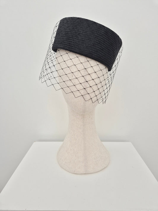 black pillbox headpiece with veiling worn on a tilt