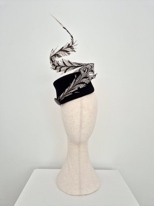 Black headband with decorative feathers on a mannequin head against a white background tilted