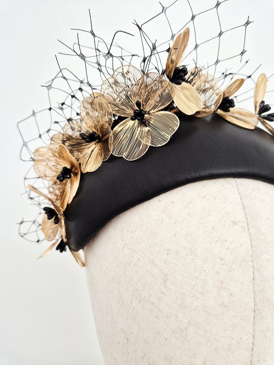 close up black leather bandeau headpiece with gold floral elements on a white background
