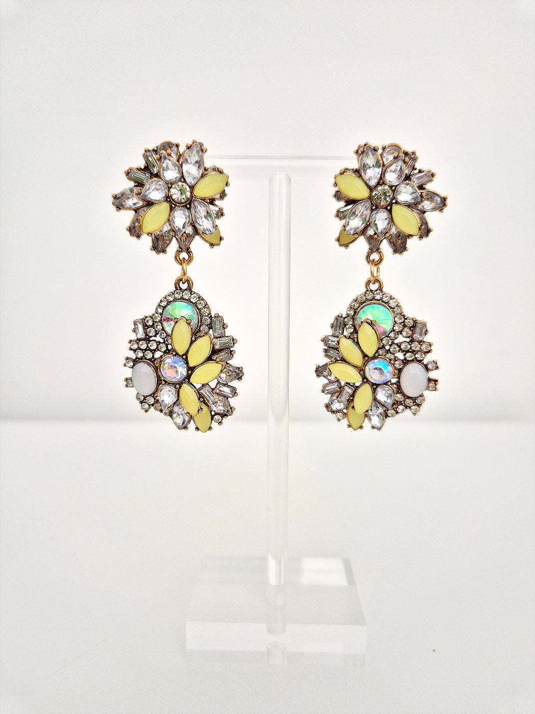 Pair of floral earrings with yellow and multicolored gemstones on a white background