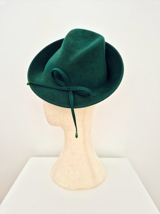 Green felt hat on a mannequin head against a white background side view