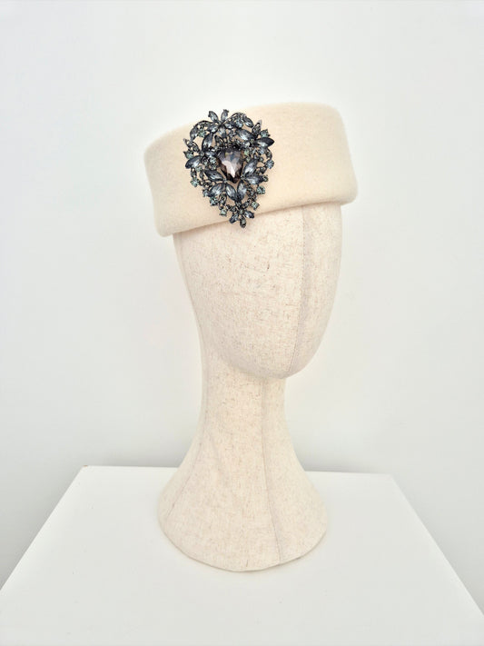 Cream-colored headband with a decorative brooch on a mannequin head against a white background side view