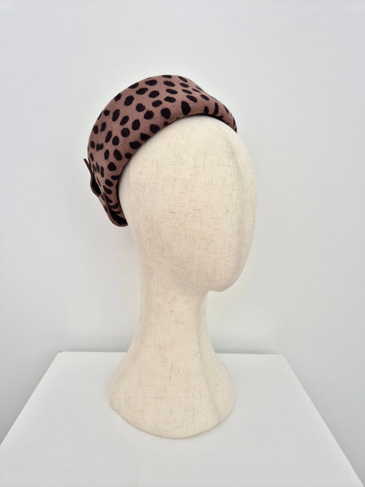 Leopard print pillbox headpiece on a mannequin head against a white background side front