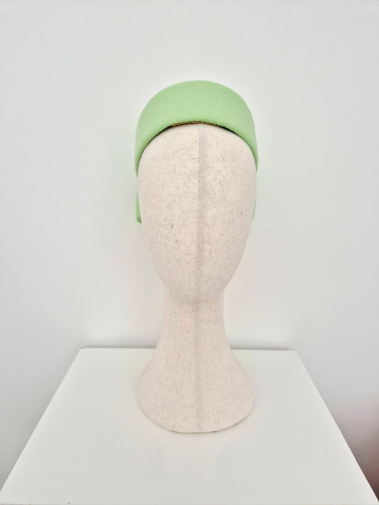 Light mint green pillbox headpiece on a mannequin head against a white background front