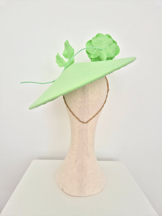 Light green hat with floral decoration on a mannequin head against a white background back view