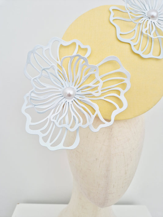 Yellow headband with white floral designs on a mannequin head against a white background close up