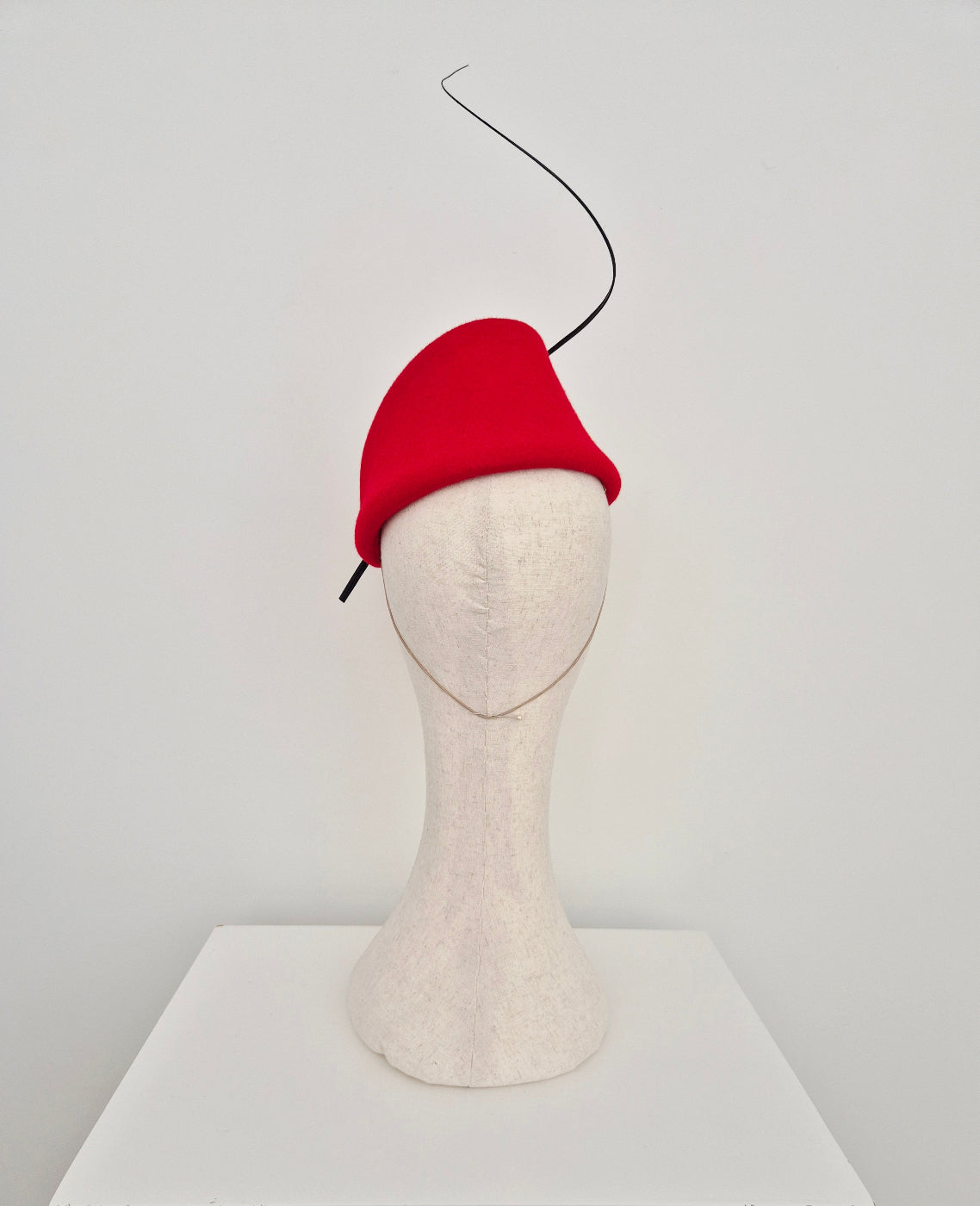 Red headpiece on a mannequin head against a white background back view