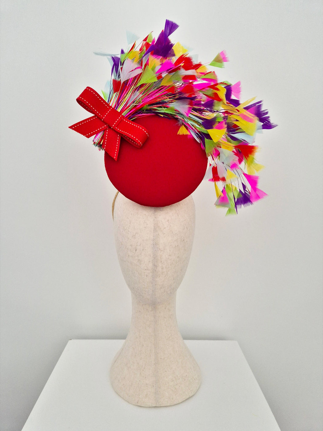 red percher headpiece with multi coloured feathers