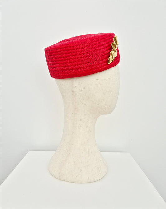 red straw pillbox with gold brooch side view