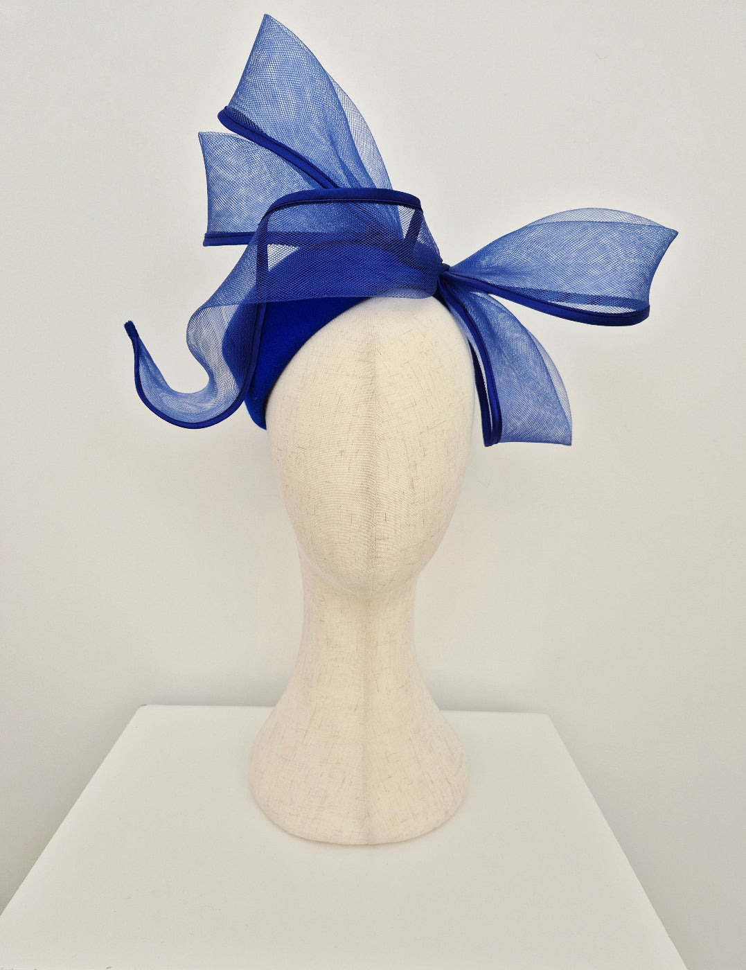 Blue bow fascinator on a mannequin head against a white background option 2
