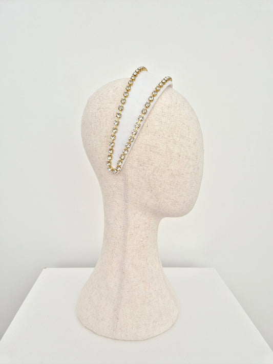 Mannequin head with white velvet headband with gold set rhinestone trim on a white background side view