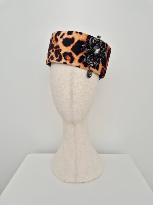 Miss Betty. Leopard print forward facing pillbox headpiece with rhinestone brooch