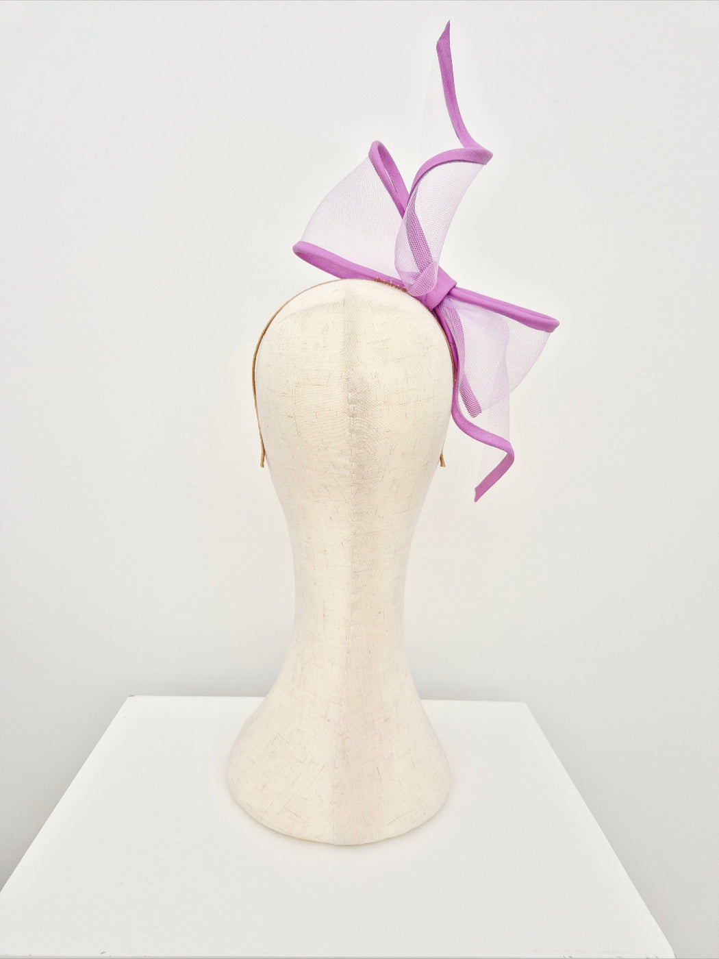 Lavender bow headband on a mannequin head against a white background back view