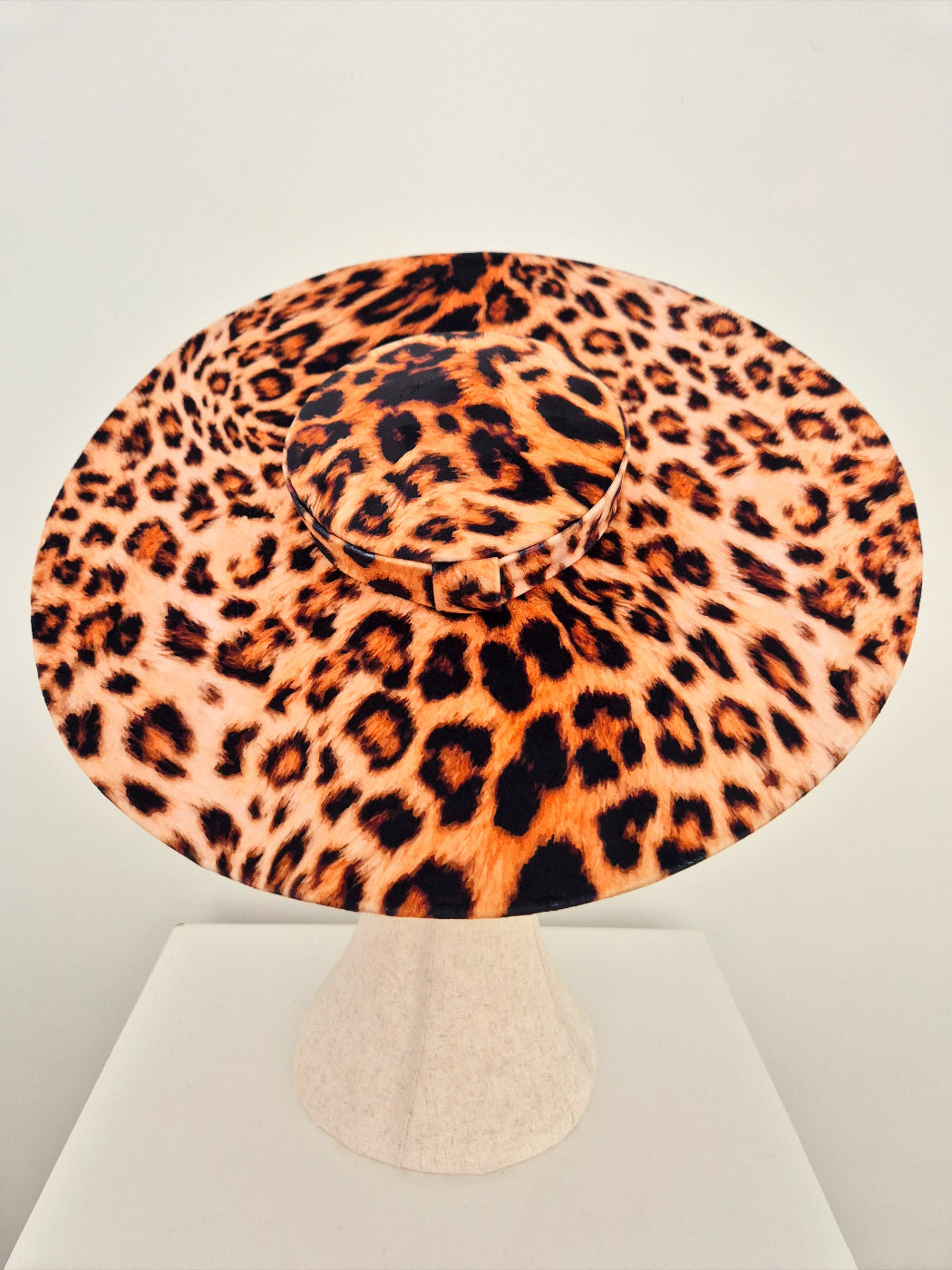 Leopard print hat on a manniquin head against a light gray background top view