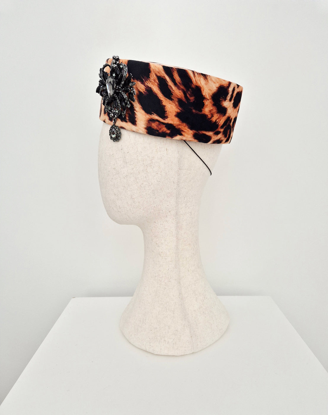 Leopard print headband with decorative elements on a mannequin head against a white background side view 2
