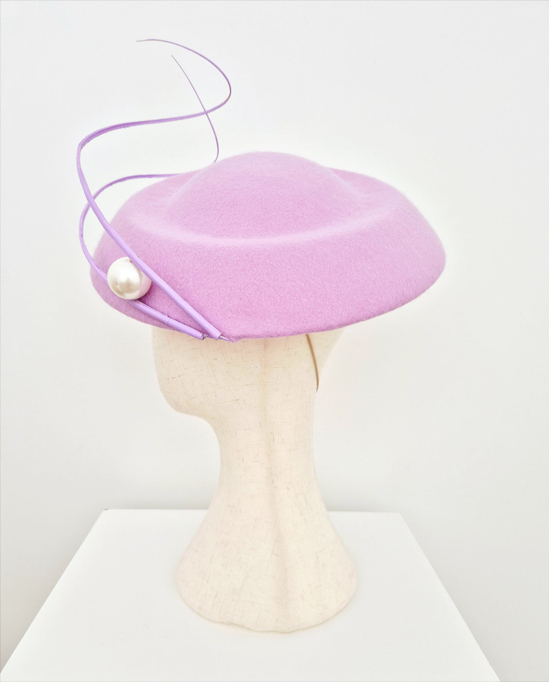 Lilac hat with a pearl on a mannequin head against a white background side view