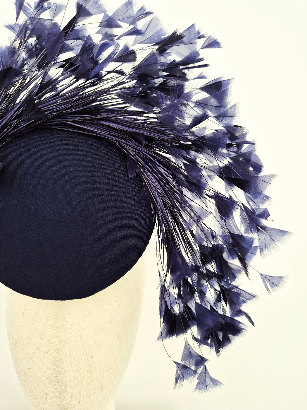 Navy blue headpiece with feathers on a mannequin head close up