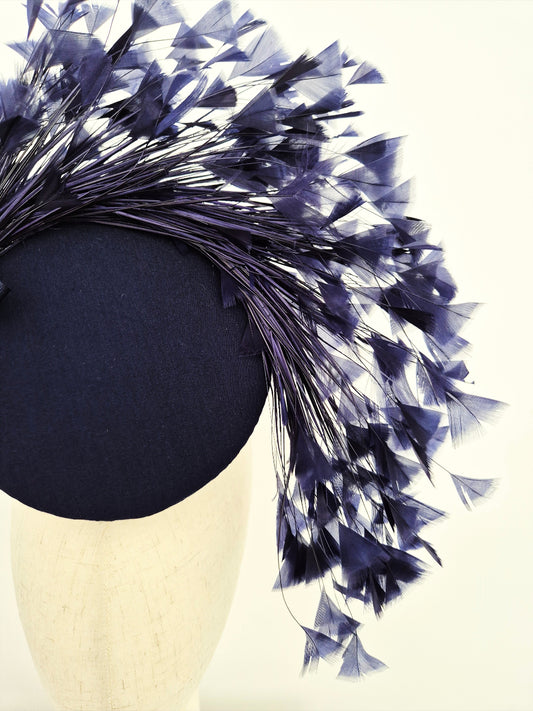 Navy blue headpiece with feathers on a mannequin head close up
