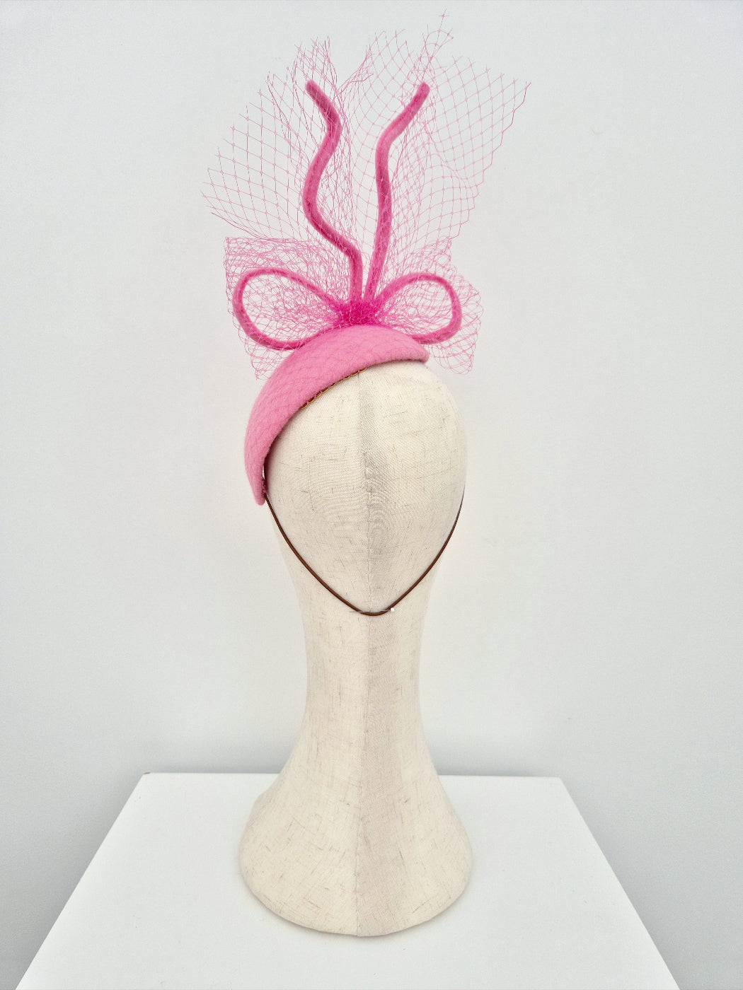 Pink headpiece with a bow on a mannequin head against a white background back view