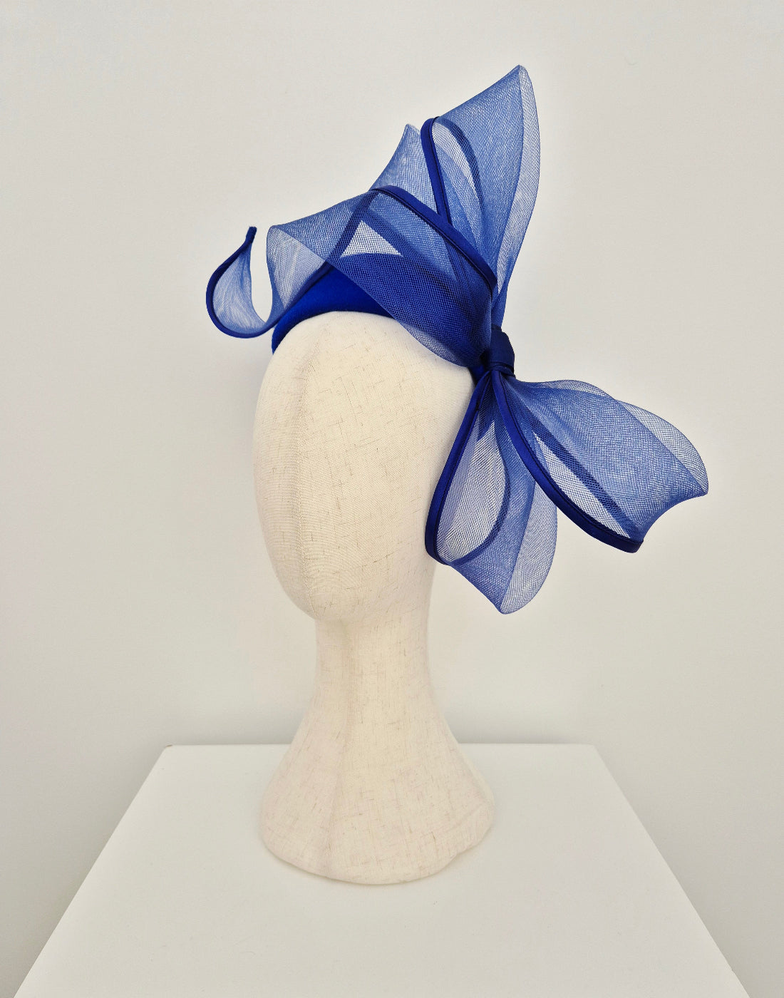 Blue fascinator pillbox  woth bow side view on a mannequin head against a white background
