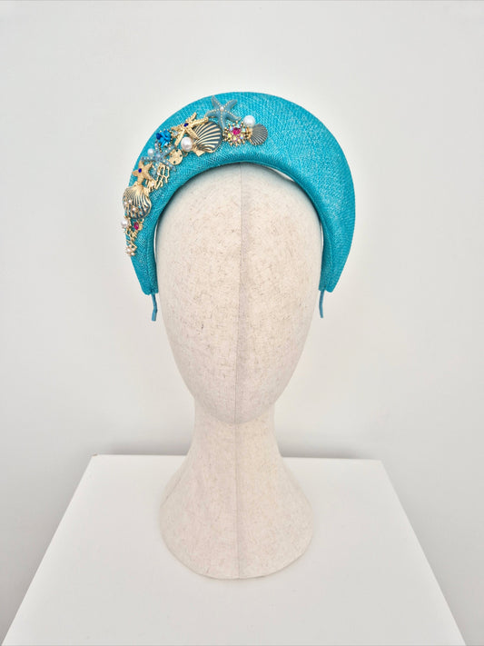 Turquoise headband with decorative elements on a mannequin head against a white background