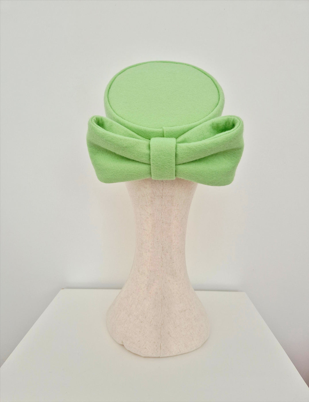 pale mint Green pillbox headpiece with bow  on a mannequin head against a white background back view