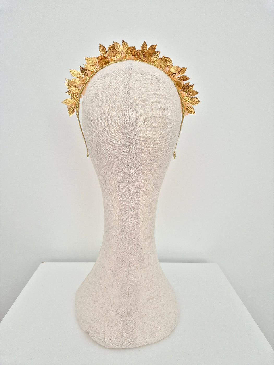 Gold headband on a mannequin head against a white background back view orange