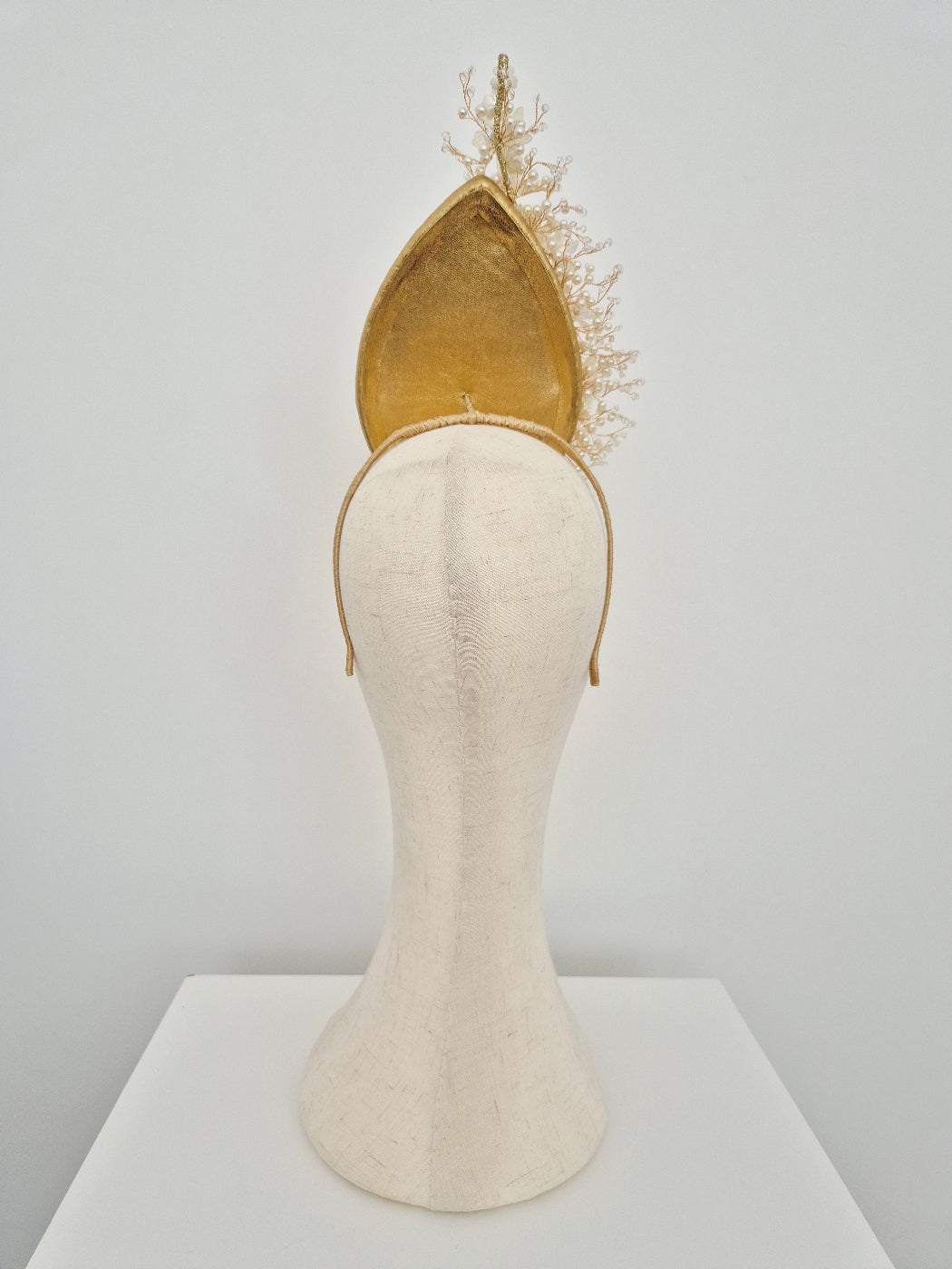 gold leather percher headpiece back view on a manniquin head
