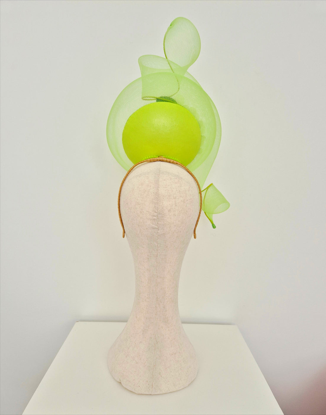 Mannequin head with a lime green  headpiece on a white background back view