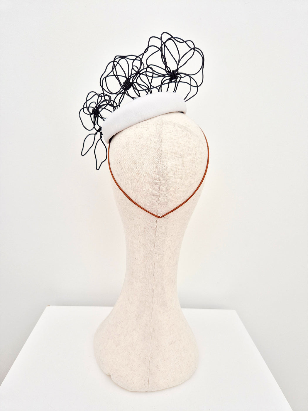 white button headpiece with black floral wirework back 