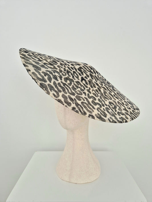 A leopard print straw hat displayed on a textured mannequin head stand against a plain white studio background. side veiw