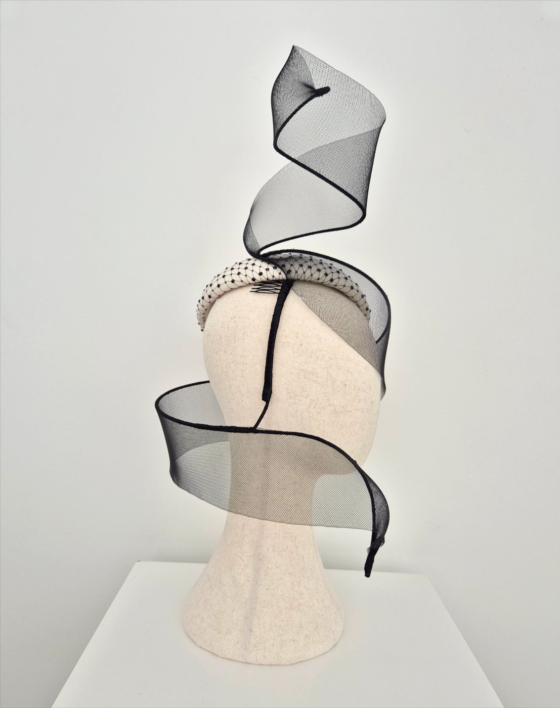 Black and ivory headpiece on a mannequin head against a plain background side