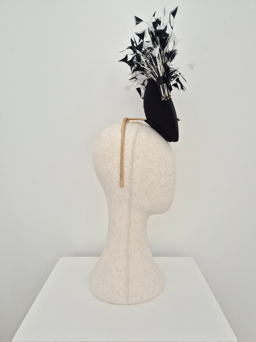 black and white feather percher headpiece side view on a manniquin head against a white background