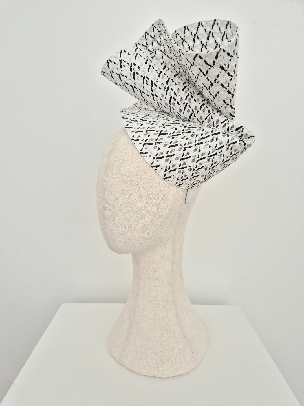 Black and white patterned headpiece on a mannequin head against a white background side view