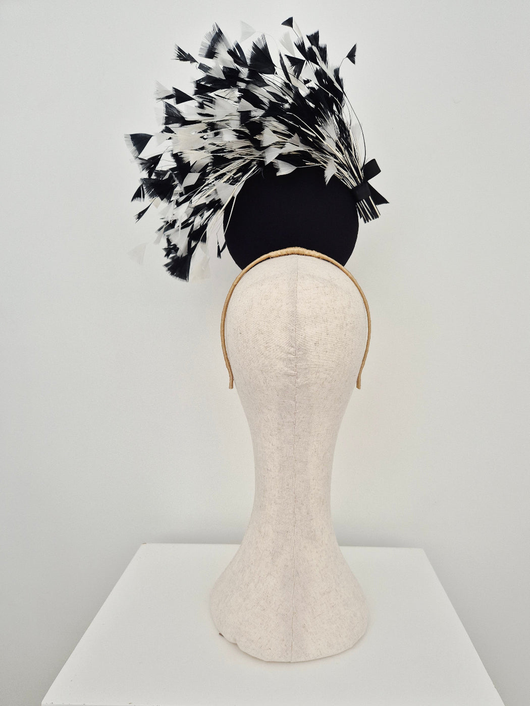 black and white feather percher headpiece on a manniquin head against a white background back view