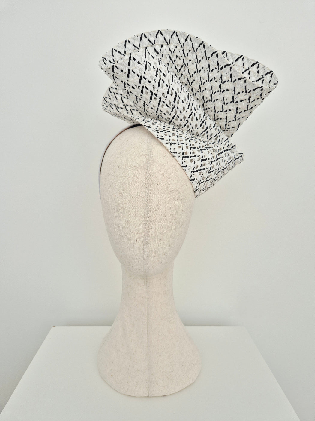 black and white straw headpiece on a mannequin head against a white background