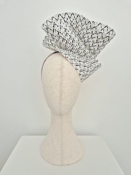 black and white straw headpiece on a mannequin head against a white background