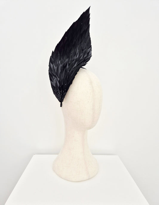 Black feathered headpiece on a mannequin head against a white background side view