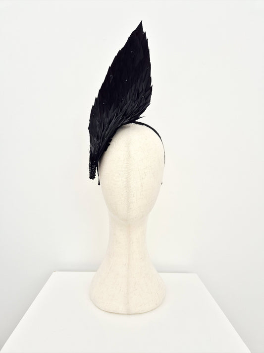 Black feathered headpiece on a mannequin head against a white background