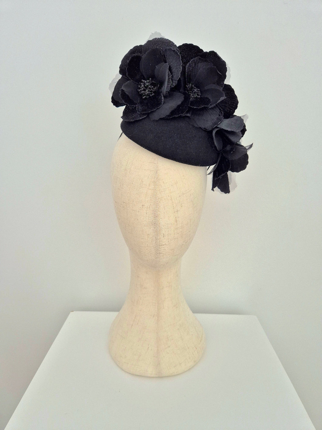 Black flower headpiece on a mannequin head against a white background