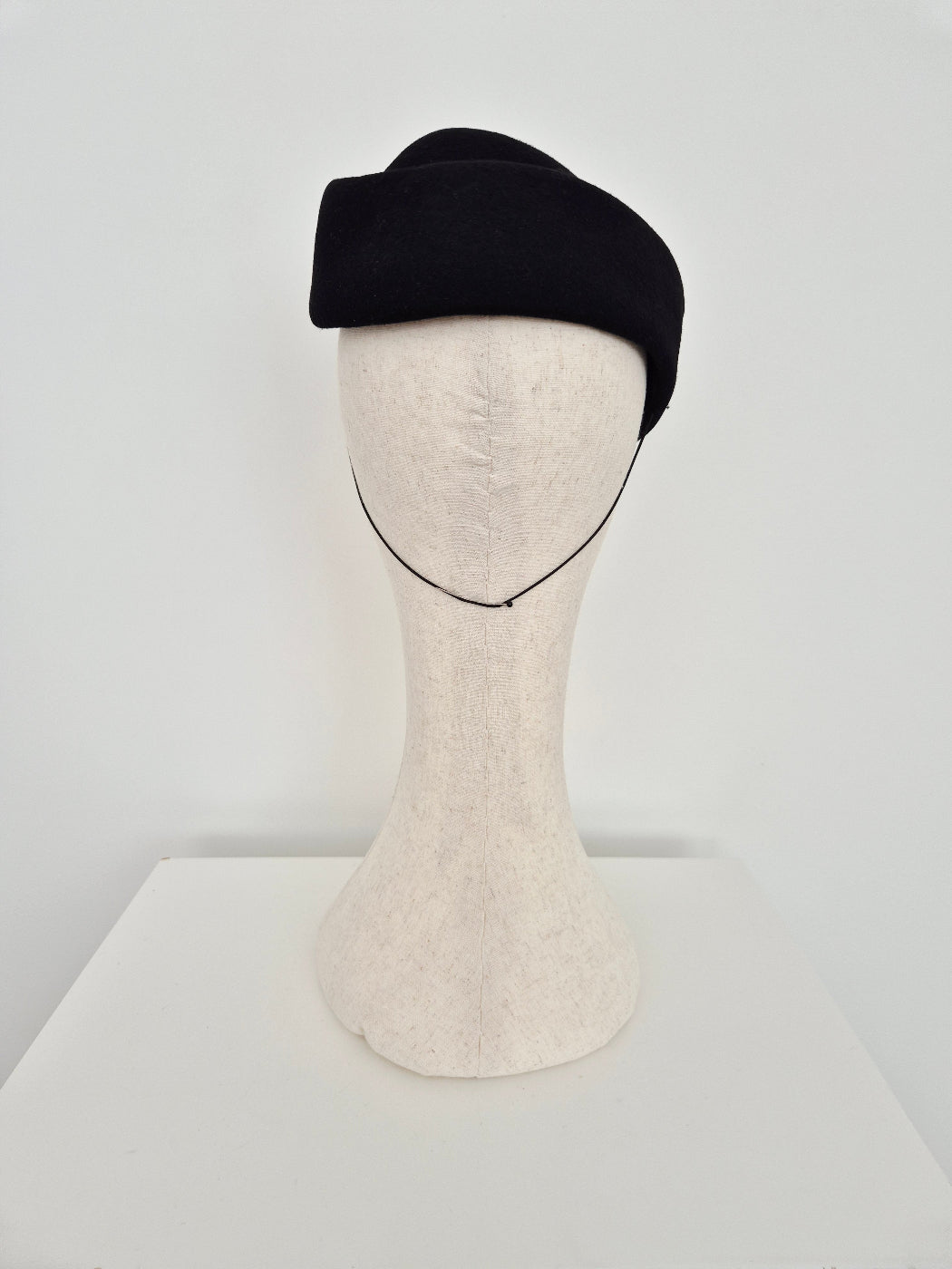 Black felt hostess headpiece on a mannequin against a white background back view