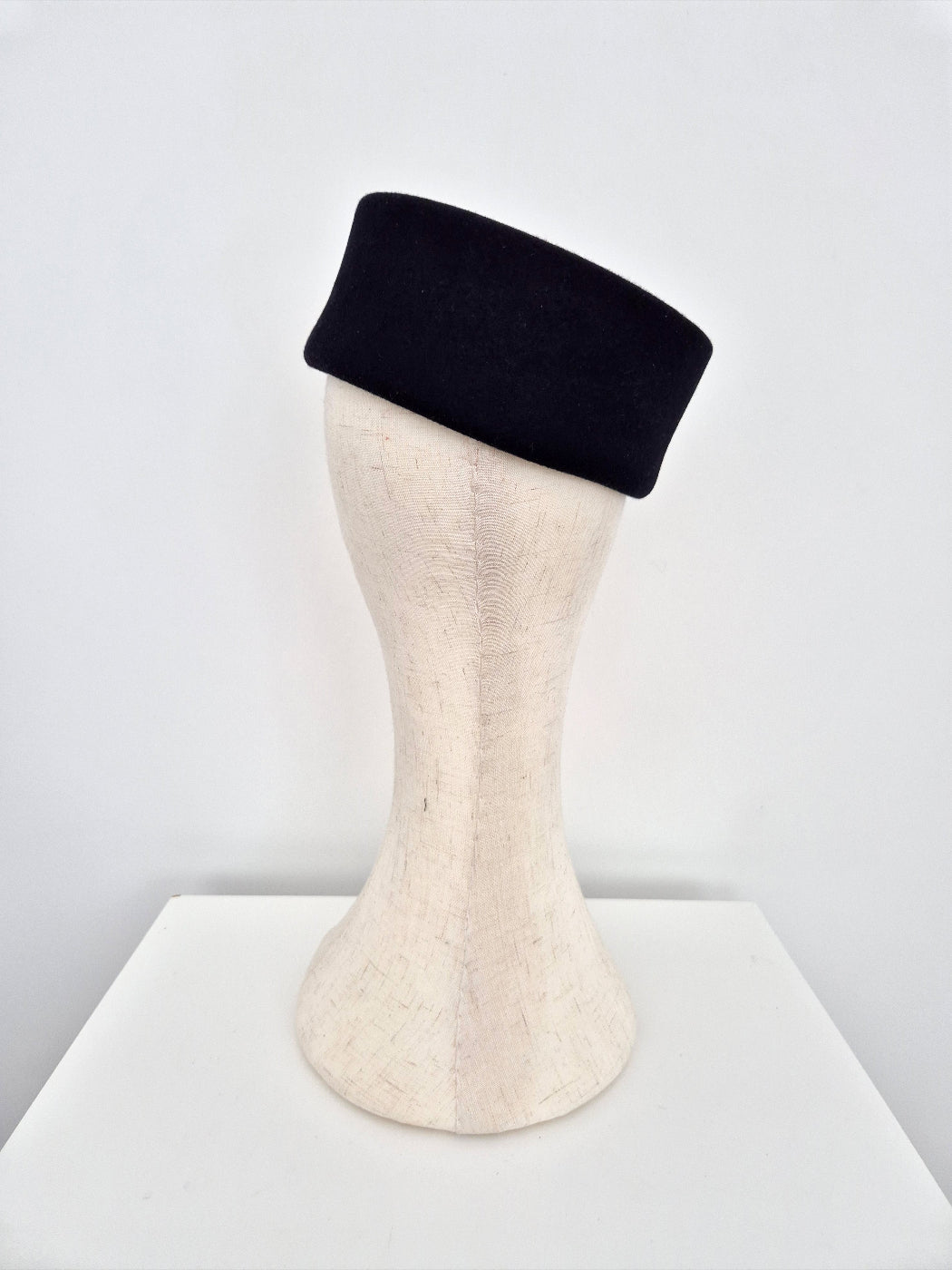 Black pillbox headpiece on a mannequin head against a white background