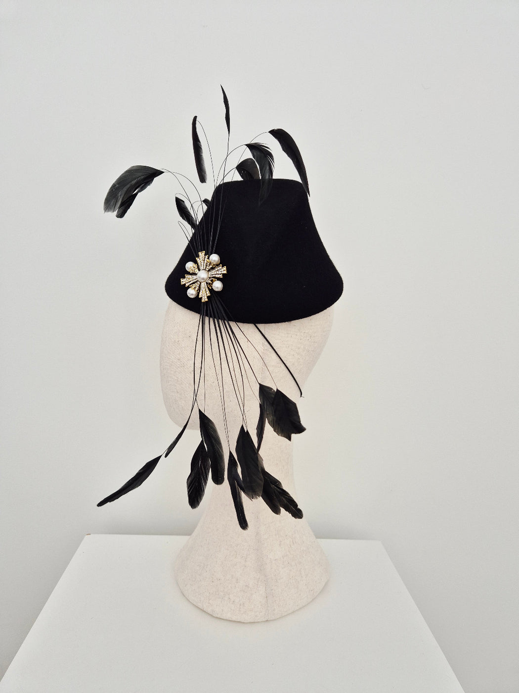 Black and white decorative headpiece with feathers on a light gray background side view