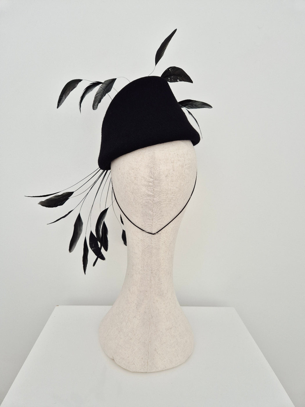 black felt topper headpiece with feathers on a white background back view