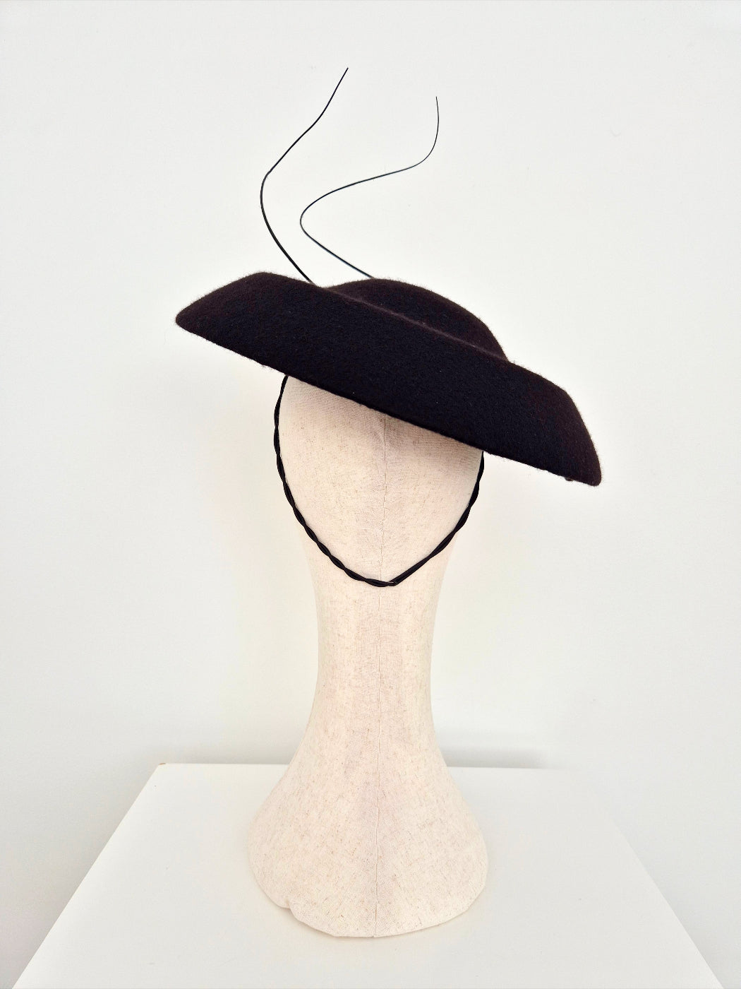 Black hat on a mannequin head against a white background back view