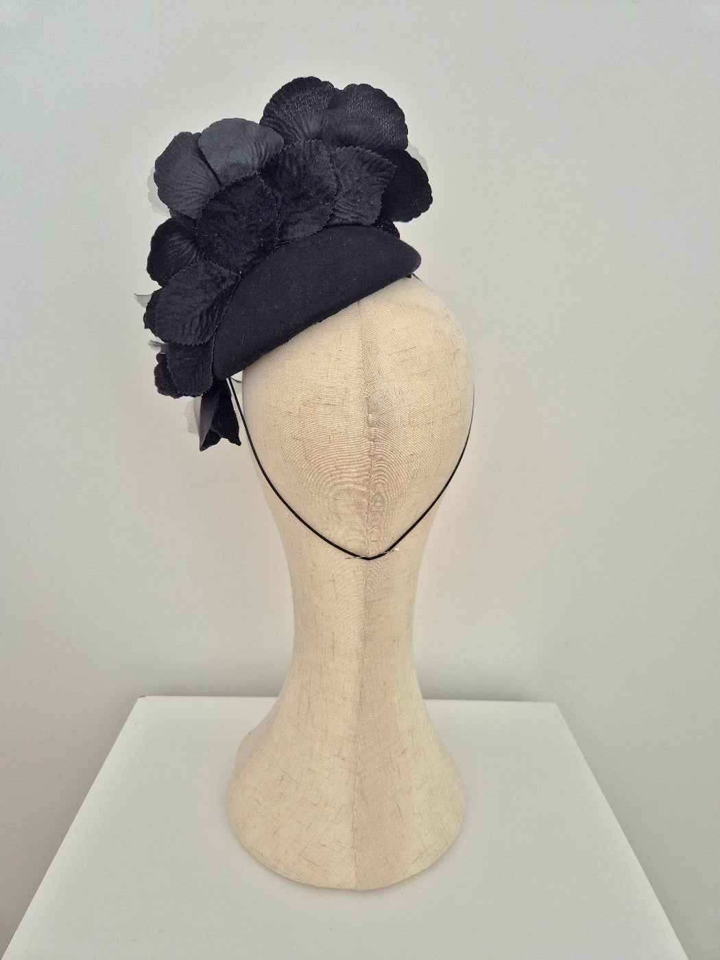 Black floral headpiece on a mannequin head against a white background back view
