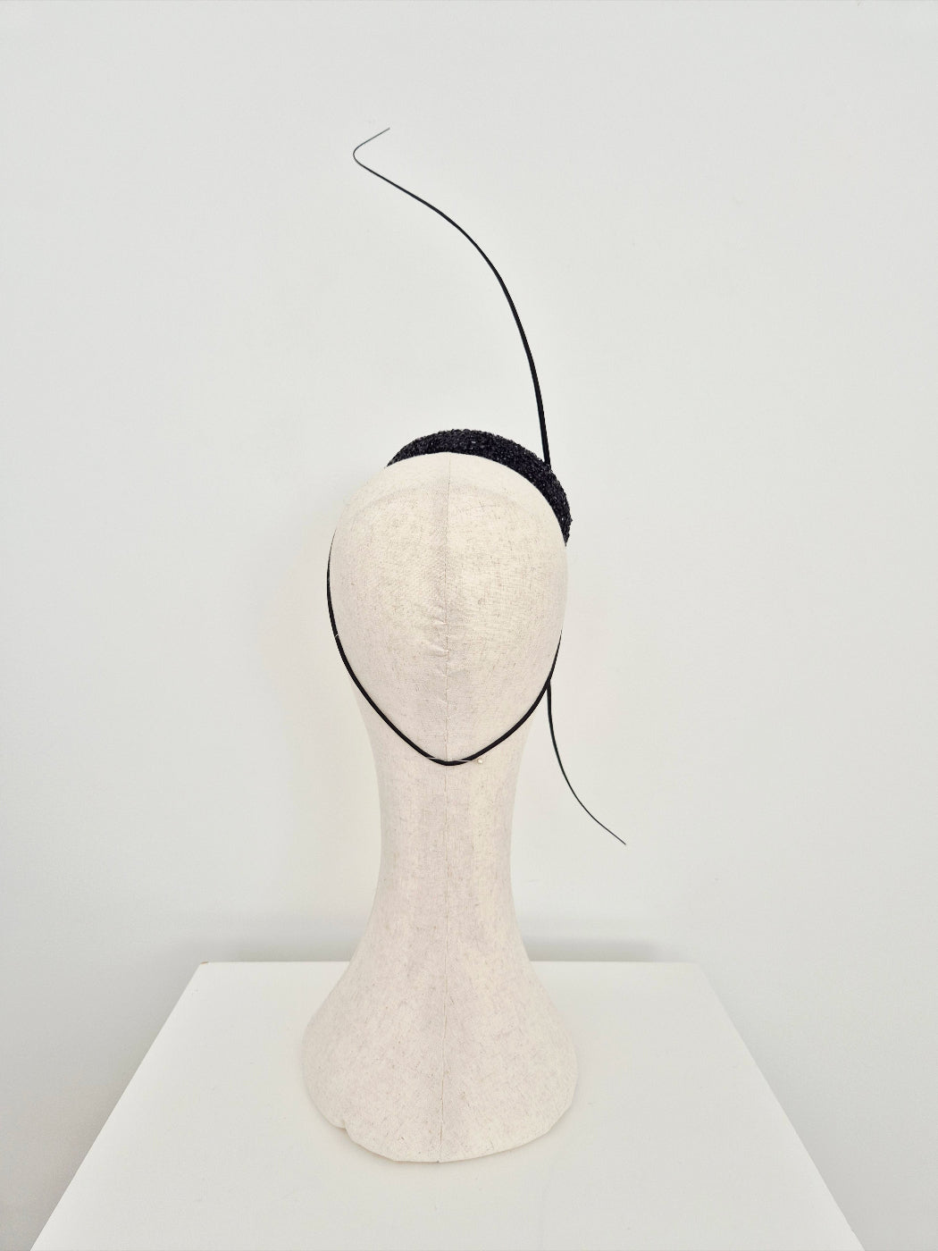 Black headpiece on a mannequin head against a white background back view