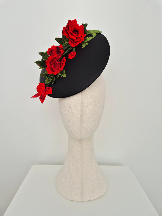 black leather percher plate headpiece with red lace floral detail on a manniquin head against a white background
